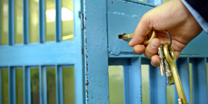 Close up photo of a hand locking a prison cell